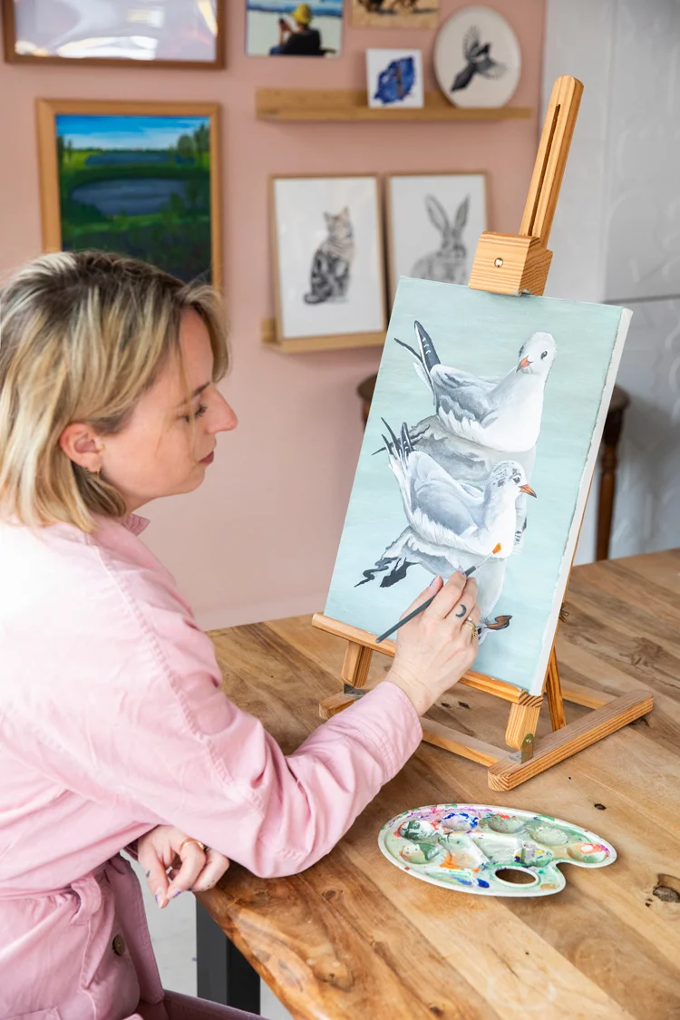 Sophie Mittelberg van Kunst-club schildert vogels op een doek in haar atelier.