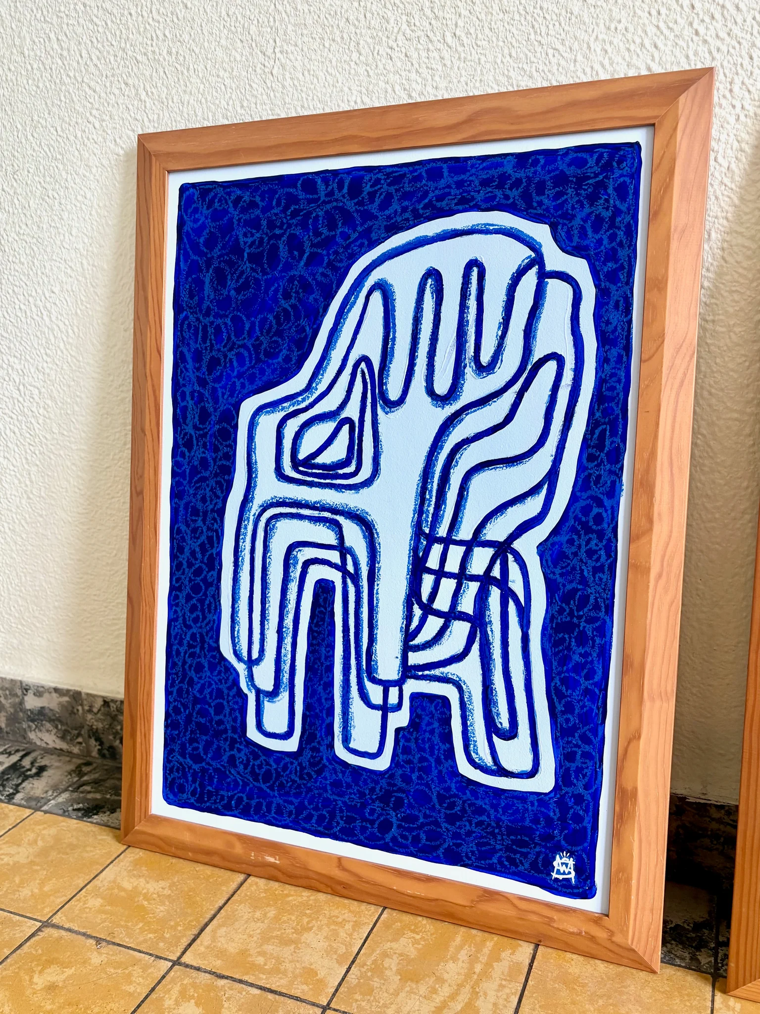 Ingelijst schilderij van gestapelde stoelen in blauwe en witte tinten.