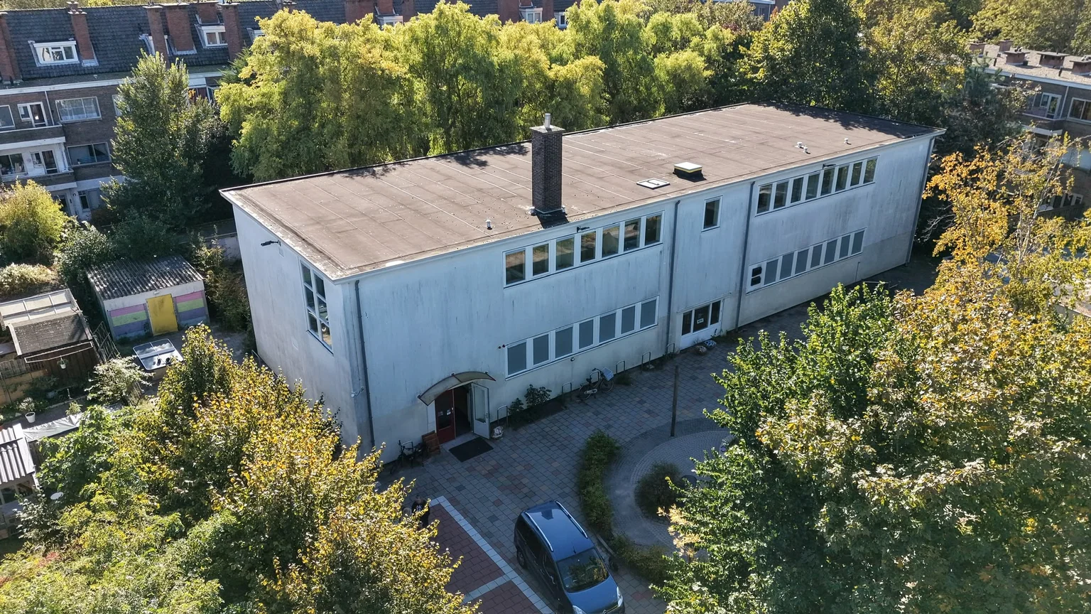 De oude school aan de Kokosnootstraat, met de ingang en de groene omgeving.